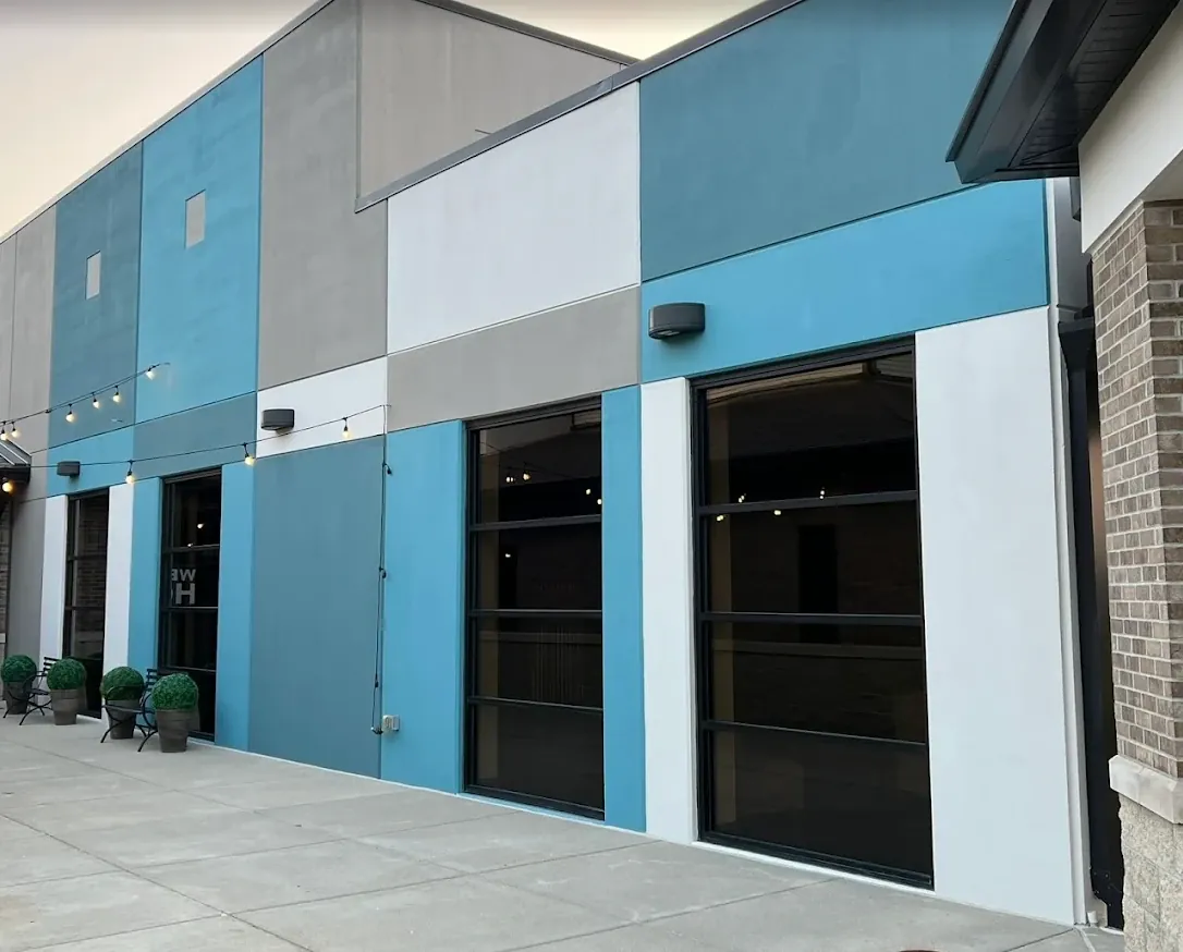 Finished retail storefront with stucco panels in teal, gray, and white around large black-framed windows